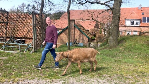 Michael Fröhlich geht mit "Hofhund" Ziege Pedro im Dorf spazieren. © NDR/DM Film/Ulla Hamann 