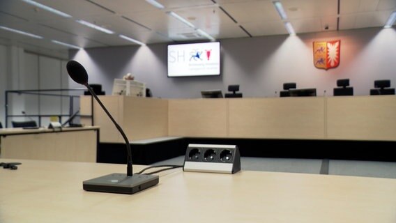 Ein Mikrofon steht auf einem Tisch in einem Gerichtssaal des Landgerichts Itzehoe. © NDR 